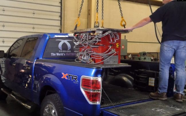 Plastic injection mold being loaded into the back of an XMD-branded Ford Pickup truck